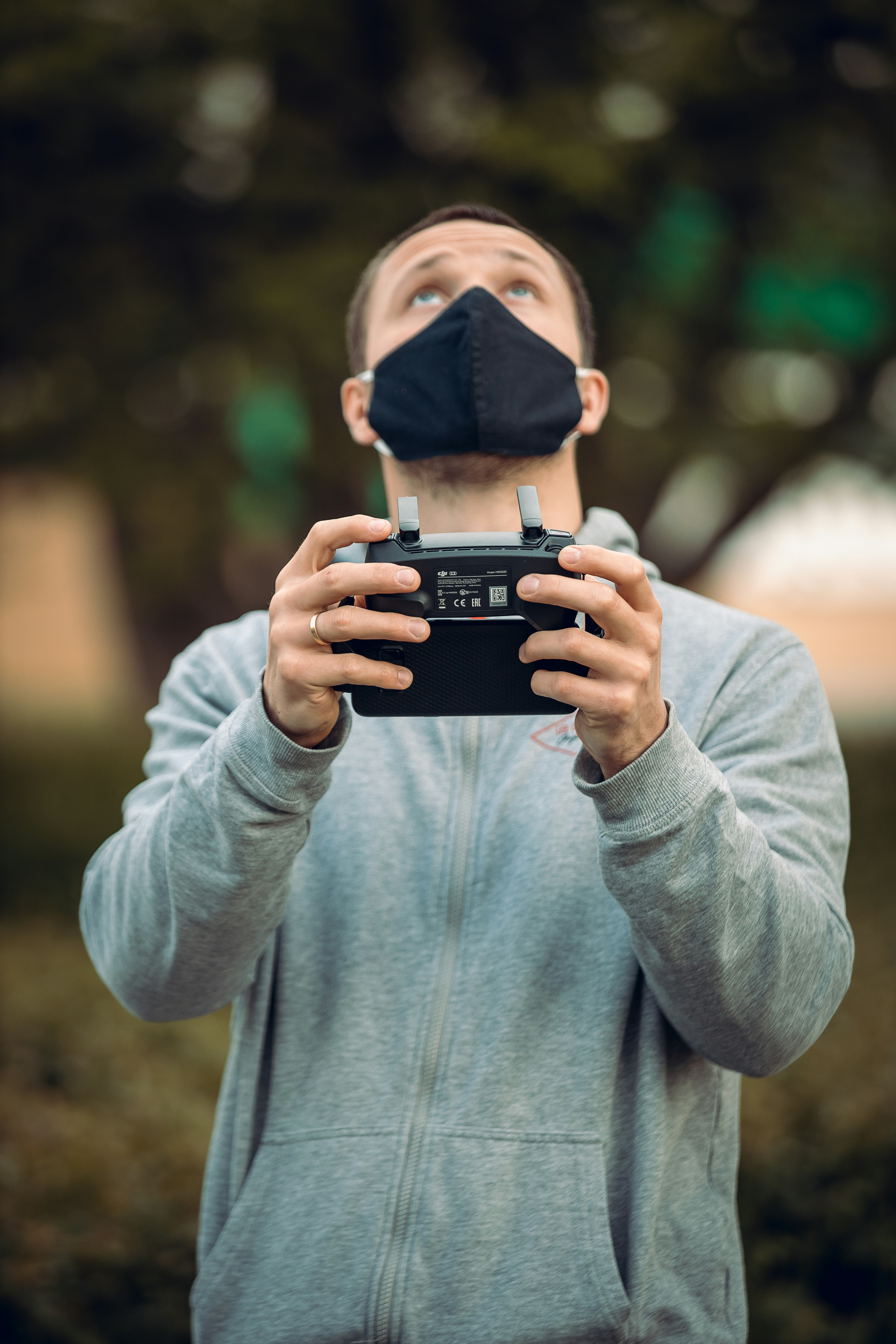 man in gray sweater holding black smartphone